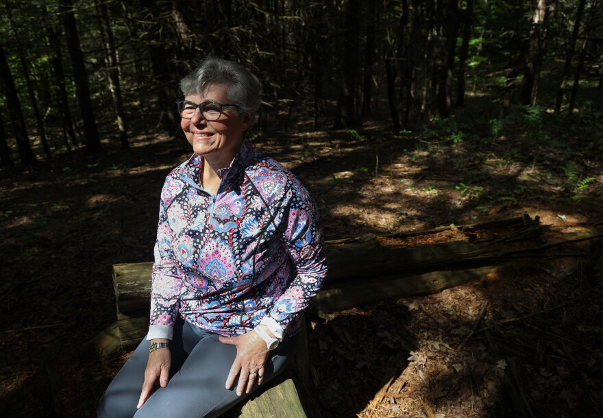 Judy Dobles sits on a log from an old log structure near a trail at Cummings Nature Center in Naples, N.Y., near where she collected moss that led to the discovery of a new species of tardigrade. Dobles, a citizen scientist and longtime volunteer at the nature center, discovered the microscopic animal, later named Misocrista ojagwaji, while examining the moss under a microscope. Tardigrades, also known as water bears or moss piglets, are microscopic, eight-legged animals known for their ability to survive extreme environmental conditions.