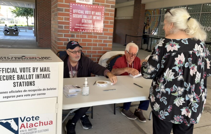 Joe Hawkins, left, and Pablo Paz, center, assist with vote-by-mail collection at the Reitz Union at the University of Florida on Oct. 22, 2026. (Anna O’Neill/WUFT News)