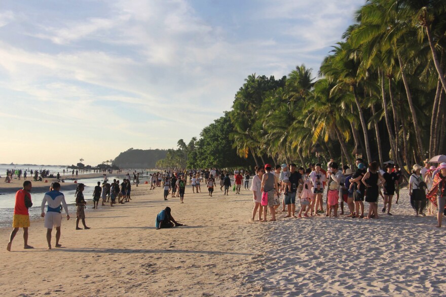 Tourists walk along a beach in Malay town, Boracay, on April 17. President Duterte's decision to close Boracay has rocked the island. The Philippines is set to deploy hundreds of riot police to keep travelers out and head off potential protests ahead of its six-month closure to tourists.