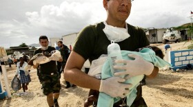 In Haiti, an Argentinean U.N. doctor carries a sick baby to a helicopter, to be taken to Port-au-Prince for treatment. The photo is part of a gallery honoring World Humanitarian Day.