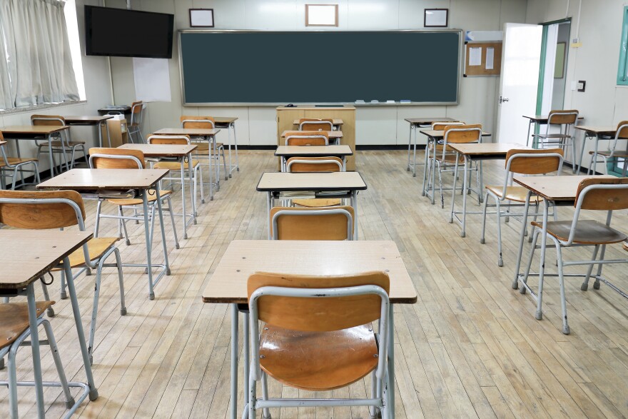 An empty classroom with lines of desks and chairs