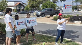 Volunterrs for the Brandon Herrera congressional campaign give away political signs.