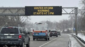 Vehicles pass a sign that reads "WINTER STORM WARNING STARTS AT 3PM" along Interstate Highway 35 near the Minneapolis-Saint Paul International Airport. (Trisha Ahmed/AP)