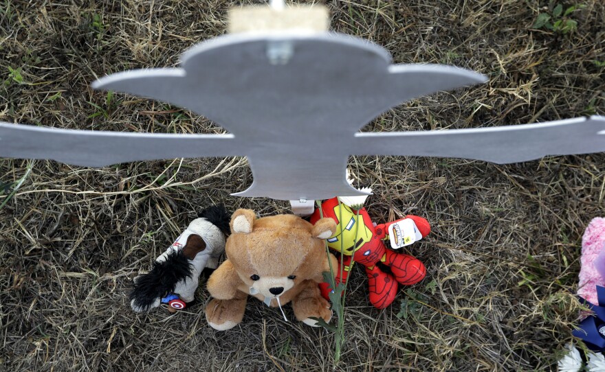 Stuffed animals sit at the base of a cross at a makeshift memorial for victims in Sutherland Springs, Texas.