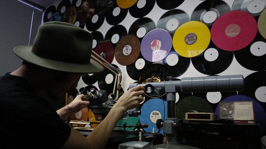 An employee demonstrates how a mother is checked for sound quality before it is duplicated during production at the Rainbo Records factory in Canoga Park, Calif. The vinyl record industry has seen an uptick in sales in recent years, keeping manufacturers like Rainbo busy.