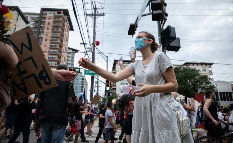 A volunteer with Dallas Street Medics receives a flower from a protester while handing out water bottles, during the Pride for Black Lives Matter protest, in Dallas.