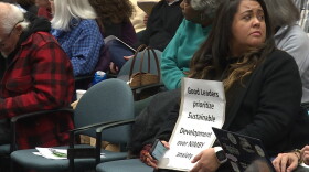 Many people in favor of multiplex housing who came to the meeting brought signs to hold while public comment was being made.
