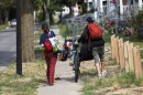 Homeless people who were cleared off a vacant city lot on Burbank Street near North Clinton Avenue carry what belonging they were able to gather on Friday, July 25, 2025, after the city of Rochester sent in operations crews and police to remove them and their tents from the vacant lot.