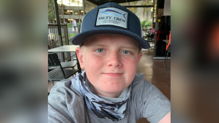 A young boy in a gray shirt and a dark grey hat