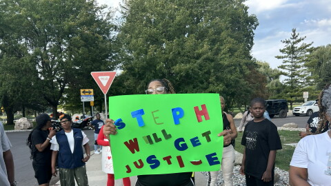 A woman displays a "Step will get justice" sign near Ojibway Park in Saginaw, Mich. on Monday, Aug. 31, 2026 ahead of the Saginaw city council meeting.