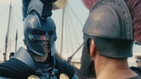 Two men looking at each other. They are dressed in ancient Greek armor with helmets.