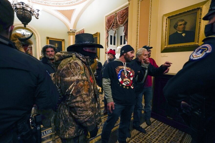 Protesters walk as U.S. Capitol Police officers watch in a hallway near the Senate chamber at the Capitol in Washington on Wednesday.