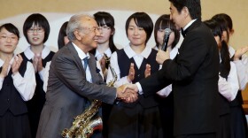 Japanese Prime Minister Shinzo Abe celebrates with saxophonist Sadao Watanabe after performing with high-school students from Fukushima in northern Japan in 2013.