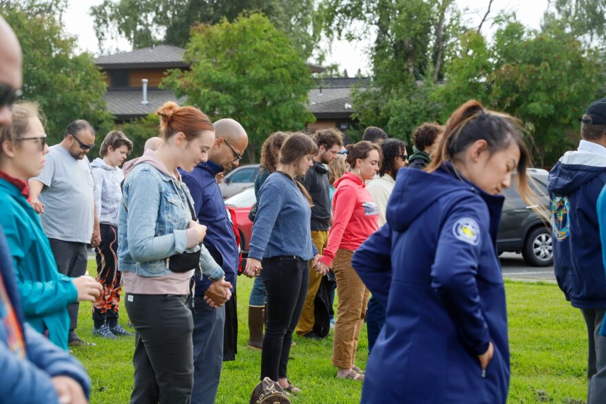 Attendees hold hands during a moment of silence at the vigil for Easter Leafa on Friday, Aug 16, 2024.
