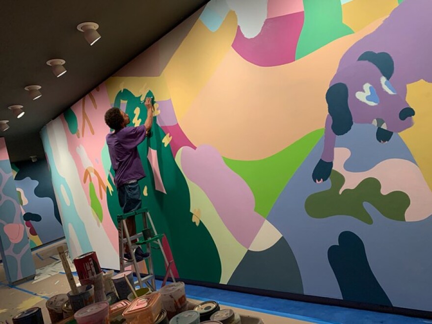 Young painting the mural "Dawgs" at the Memoral Art Gallery's Hurlbut Gallery.