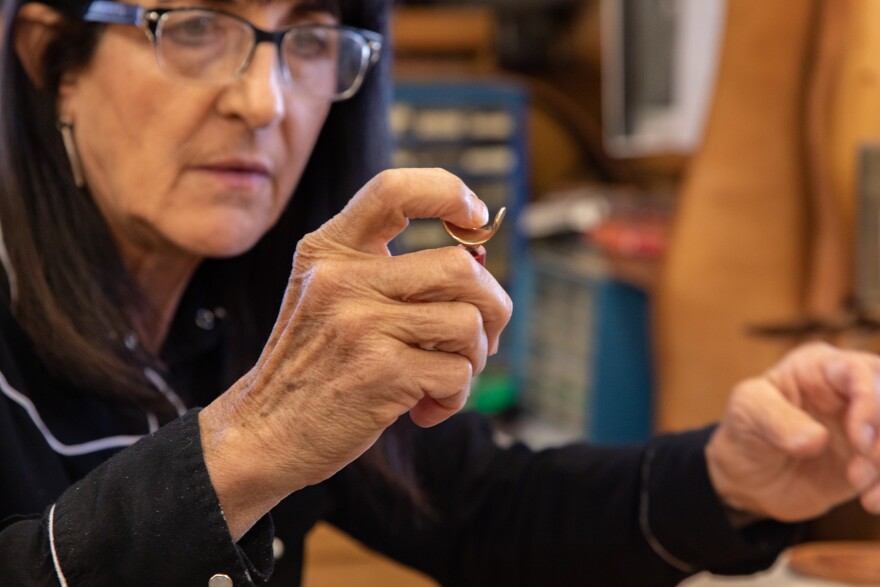 A woman holding a swivel knife, showing the different parts. 