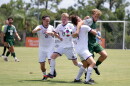 3 soccer players in white uniforms compete with a player in green for a loose ball