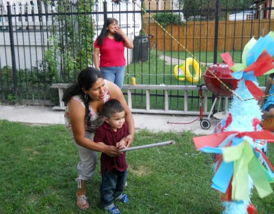 A woman helps a child take aim at a pinata