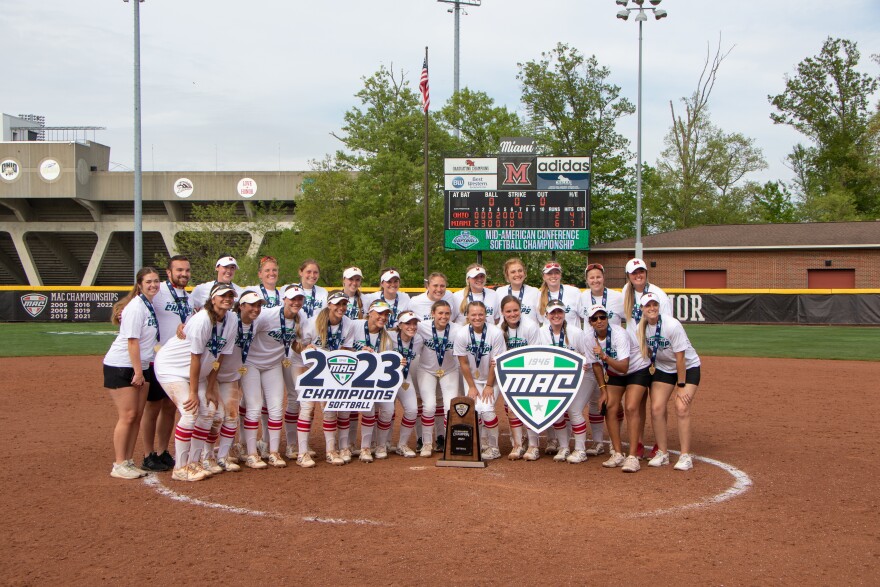 softball team in uniform poses for photo with 2023 mac championship logos