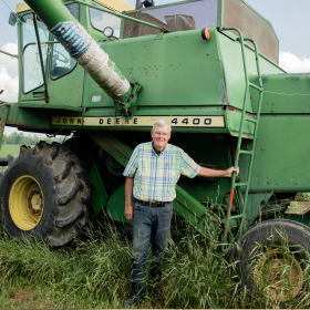 Dennis Kellogg proudly stands next to his John Deere combine from the 1970s. He said he'll use this equipment to harvest his crop later this year.