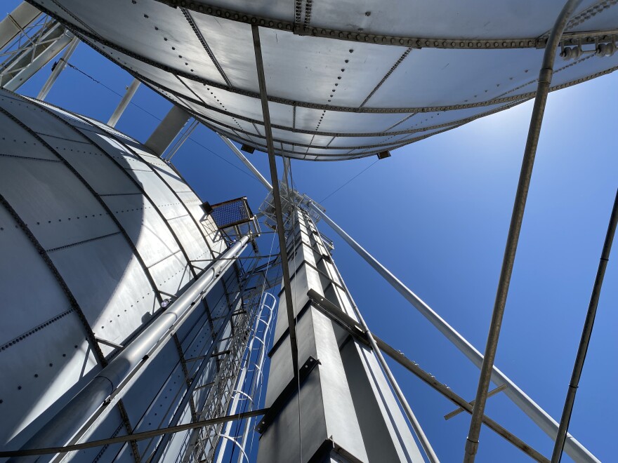 A mechanism that shuttles grain, called a leg, spires into the sky amid the bins at Northwest Grain Growers in Walla Walla. The leg carries grain dumped from trucks into receiving pits, up in buckets, sometimes well over 100 feet before the grain gets distributed to the many different grain bins and storage facilities (Credit: Anna King / Northwest News Network)