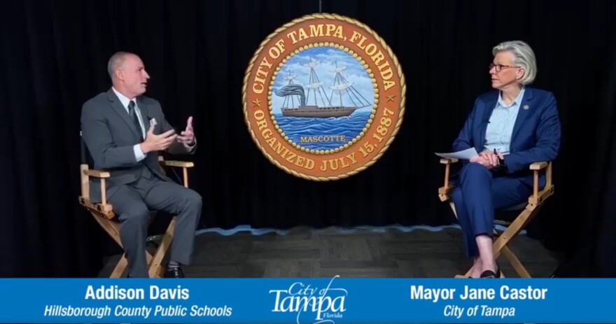 man and woman sit on chairs and speak to each other in front of City of Tampa seal