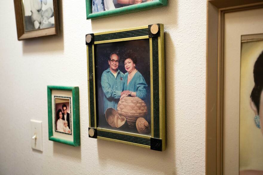 A photo of a couple dressed in denim posing with baskets is surround by other photos on a wall.