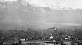 A black and white photo of some small homes against the backdrop of the mountains