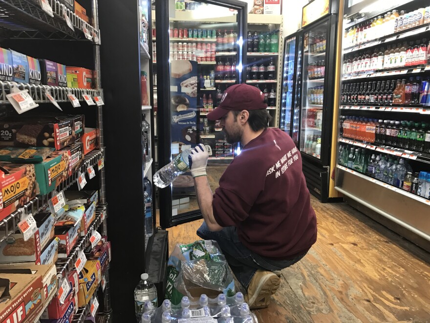 A worker restocks a cold soda display. Soda distributors in Philadelphia say sales are down and they have had to let employees go since the city's tax on sweetened drinks went into effect.