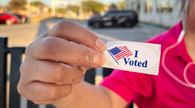A Denton County voter holds up her “I Voted” sticker after casting a ballot in 2024.