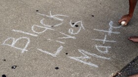 A protester writes, "Black Lives Matter," on the ground with a chalk as protesters gather, Friday, Sept. 15, 2017, in downtown St. Louis, after a judge found a white former St. Louis police officer, Jason Stockley, not guilty of first-degree murder in the death of a black man, Anthony Lamar Smith, who was fatally shot following a high-speed chase in 2011. (AP Photo/Jeff Roberson)