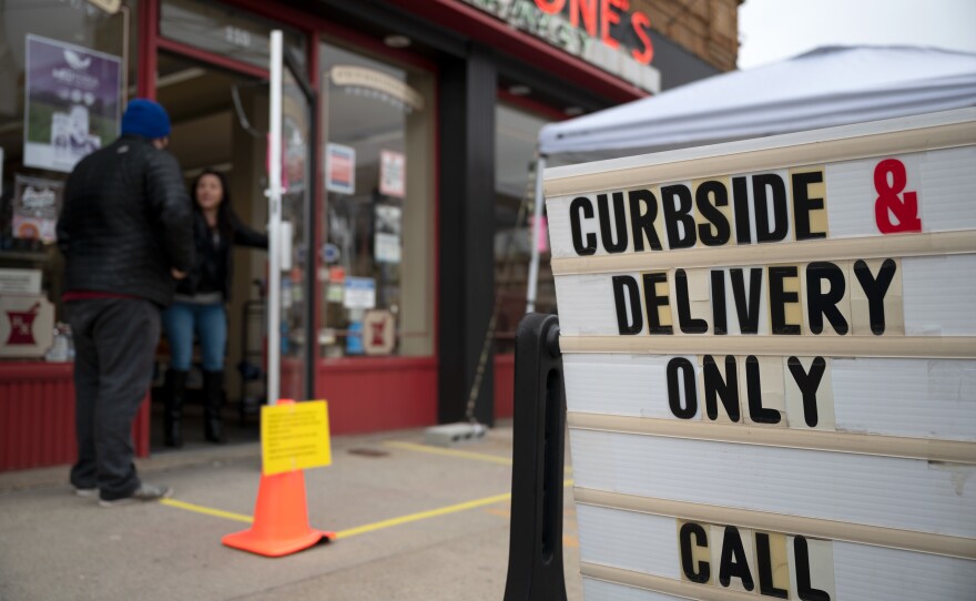 A pharmacy staff member lets another worker into Petricone's Pharmacy in Torrington, Connecticut, on March 25, 2020.