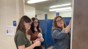 Nova Paulk, Haleigh Engle and Chera Wackler install a period product caddy at Soldotna High School.