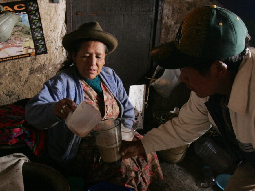 A woman serves a glass of 'Chicha' to a client in the village of Pisaq near Cuzco, Peru. Chicha is a local alcoholic beverage made from sprouted or germinated corn.