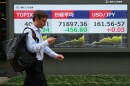 A man walks past monitors showing Japan's Nikkei 225 index, center, and a foreign exchange rate of the Japanese yen against the U.S. dollar at a securities firm in Tokyo, Tuesday, June 23, 2026.