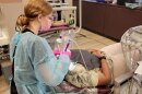 Dental student in full PPE performs a cleaning on a patient at a clinic.