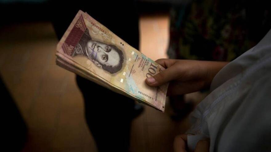 A Venezuelan holds a stack of near-worthless 100 bolivar bills at a shop in Caracas this year.