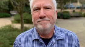 Photograph of Tom Carpenter wearing a blue shirt with white hair and white goatee