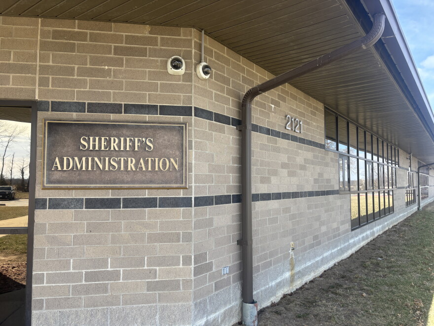 Exterior of Boone County Sheriff's administrative building. A mounted placard with gold lettering on a beige brick wall reads "Sheriff's Administration," with the address number 2121 displayed on the wall to the right of the placard.  