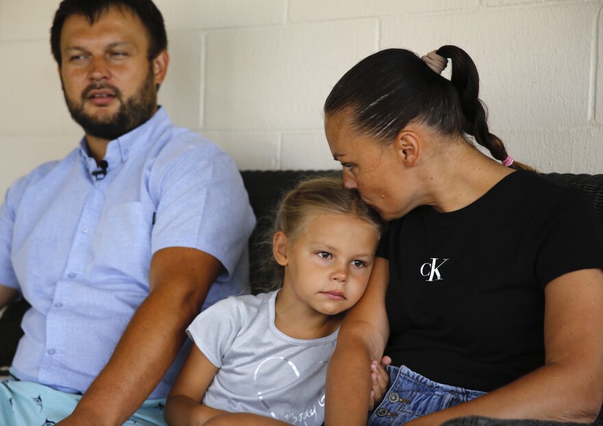 Vasyl Prishchak, left, is interviewed by The Associated Press as his wife, Marina, right, and daughter, Ksenia, 5, sit next to him at their temporary home in Kailua, Hawaiʻi, Wednesday, March 23, 2022. (AP Photo/Caleb Jones)