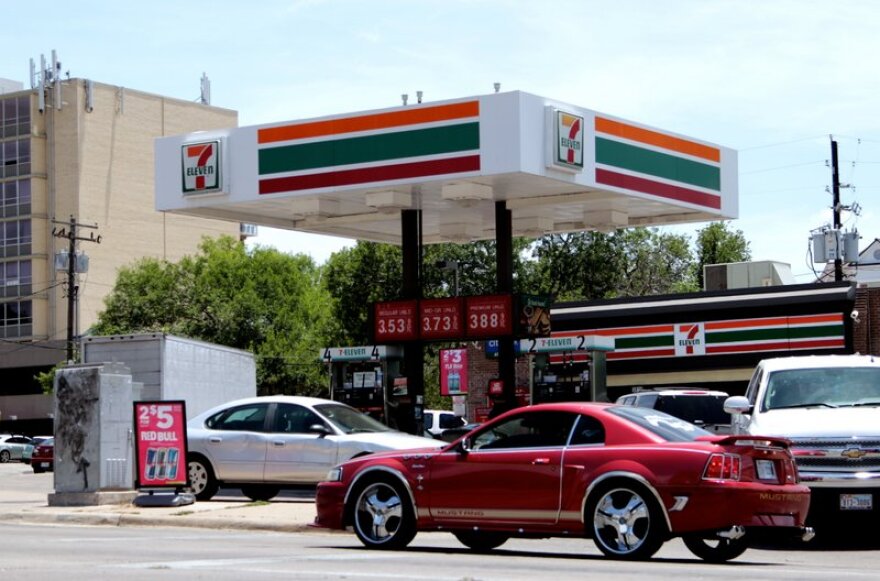 A photo of the 7/11 gas station at Guadalupe and MLK Boulevard with a red car in front of it. 