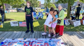 Two campers and WNY Peace Center Interim Co-Director Vicky Ross goof around while taking a photo after a press conference on July 31, 2026 at Canalside.