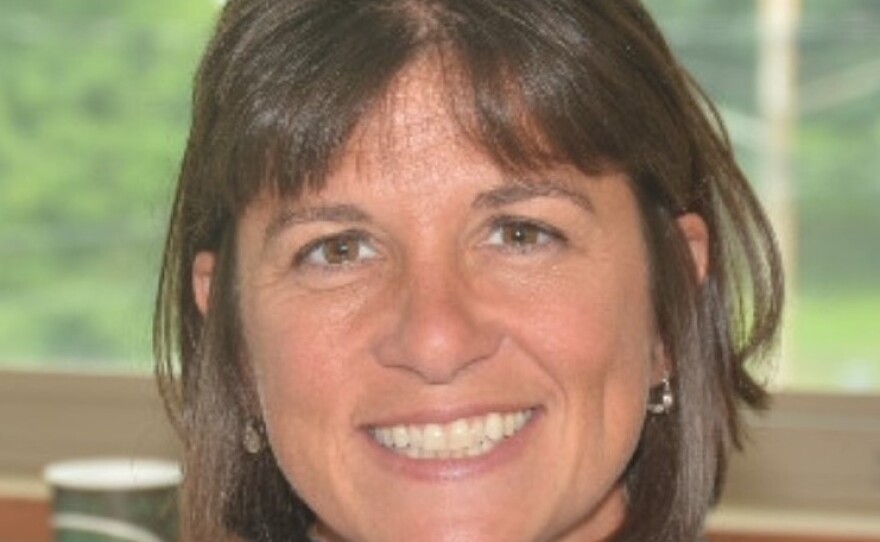 A smiling woman is wearing a blue shirt.