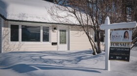 A for sale sign in front of a white house.