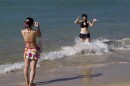 FILE - In this March 11, 2011 file photo, two visitors from Japan take pictures of each other in the waters of Waikīkī Beach in Honolulu. (AP Photo/Marco Garcia, File)