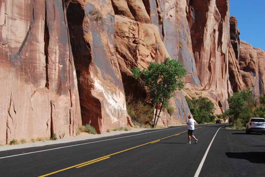 A visitor to Moab crosses the highway to get a better look at a petroglyph panel.