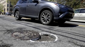 A vehicle maneuvers around a pothole outlined by paint near a manhole along Summit Avenue, Tuesday, April 23, 2019, in Jersey City, N.J. (Julio Cortez/AP)