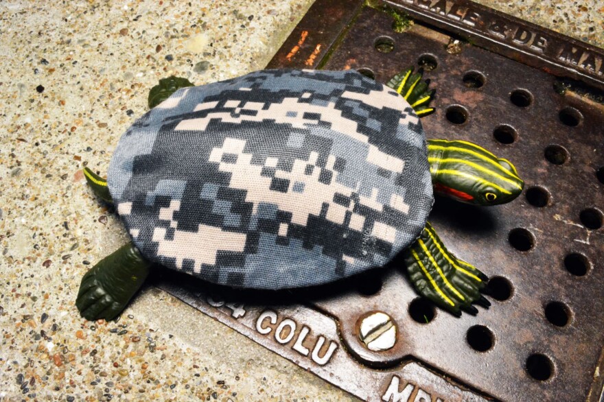Military camouflage designed for urban combat allows reptiles to elude detection in cities as urbanization overtakes their natural habitats. In this model, a turtle wears a camouflage fabric shell covering. (Courtesy)