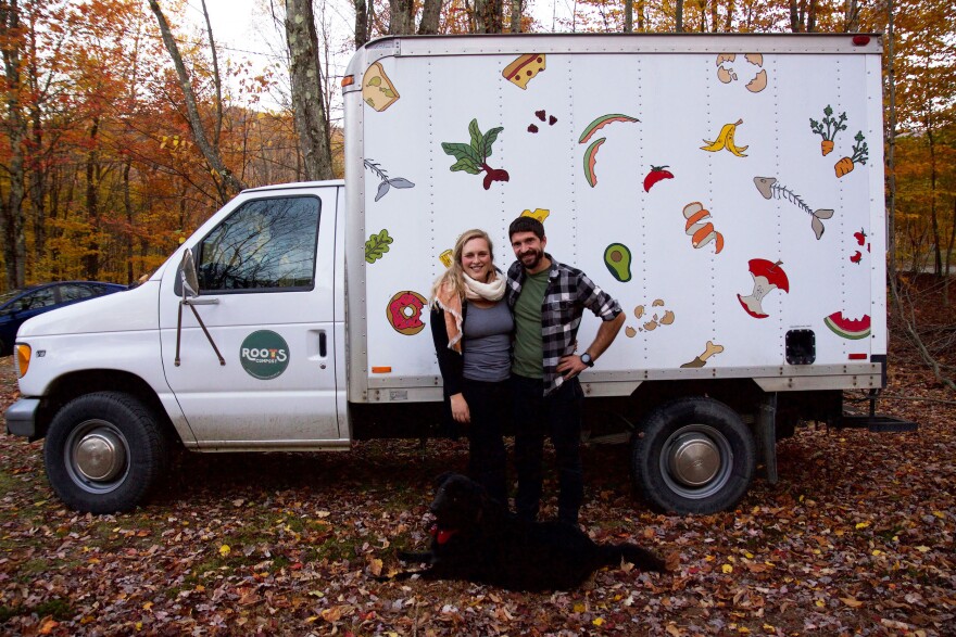 A couple with a dog in front of a truck with prints of vegetables and fruit on it.