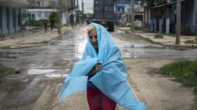 A resident uses plastic as protection from the rain in Batabano, Cuba, Monday, Sept. 26, 2022. Hurricane Ian was growing stronger as it approached the western tip of Cuba on a track to hit the west coast of Florida as a major hurricane as early as Wednesday. (AP Photo/Ramon Espinosa)